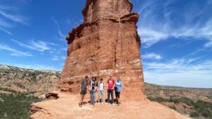 Students standing in a red colored canyon with a blue sky