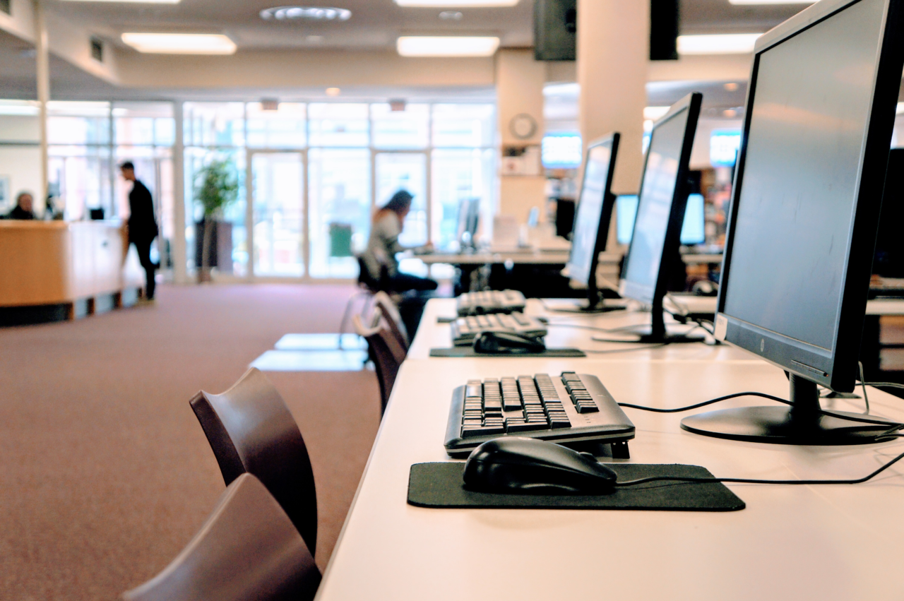 Row of computers with students in the background