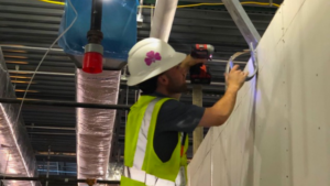 Man in safety vest drilling into wall