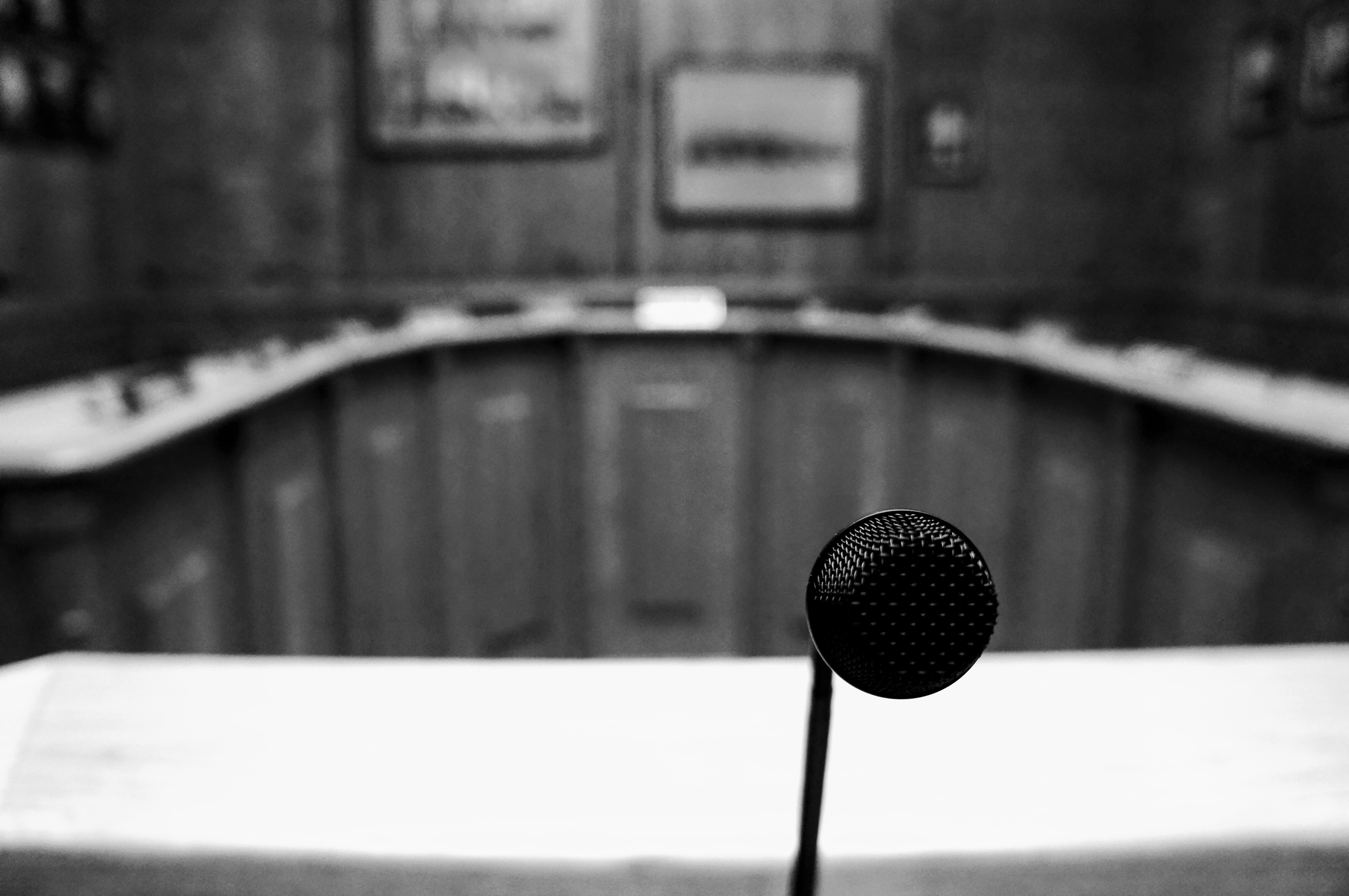 Greyscale image of microphone in foreground and meeting chambers in background
